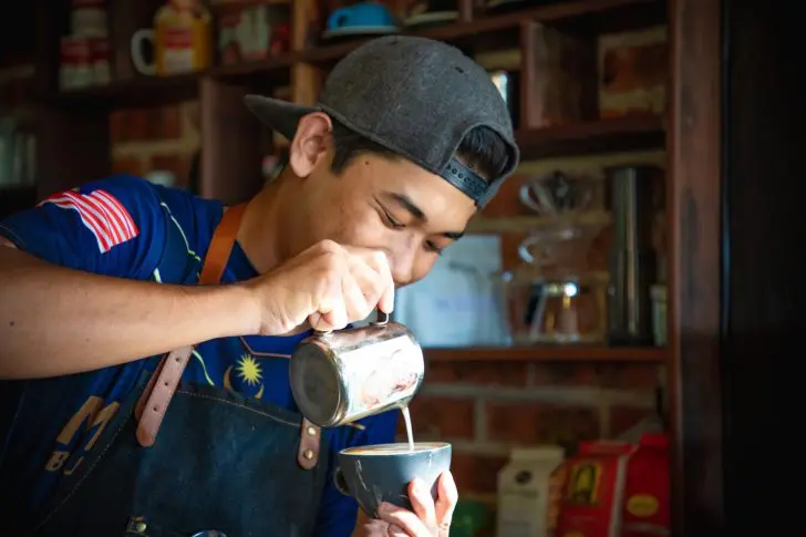 笑顔でコーヒーを淹れる男性の画像